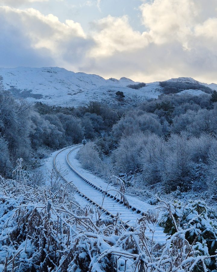 A railway line curving through snow-covered hills in Scotland