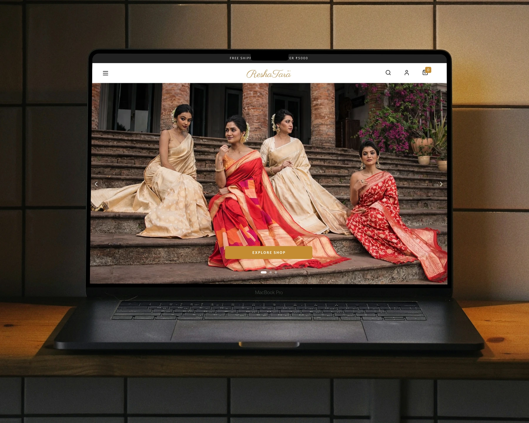 The Reshatara landing page on a laptop: four women in Banarasi silk sarees on stone steps