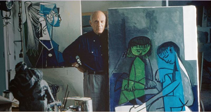 Picasso in his studio beside a painting